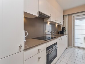 A modern kitchen with white cabinets, stainless steel appliances, and a large window providing natural light. - 2 bedroom accommodation in Wenduine (Wenduine)