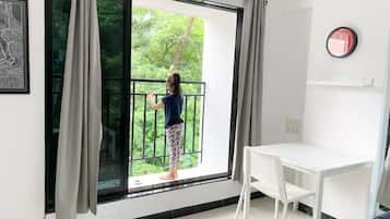 A room with a large window, a white table, and a framed picture on the wall.