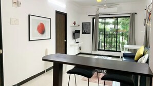 Un salon moderne comprenant un coin repas, une grande fenêtre donnant sur un espace verdoyant et un ventilateur de plafond.