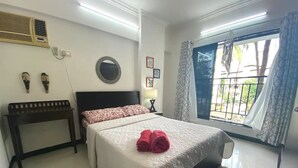 Une chambre à coucher comprenant un lit, une table de chevet, un climatiseur fixé au mur, une fenêtre avec des rideaux et une vue sur l’extérieur.