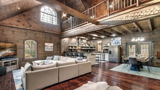 A spacious living area with a large sofa, a dining table, and a kitchen in the background. - 🏡 Luxury Smoky Mountain Retreat | Mega Spa, Game Room & Stunning Views (Cosby)