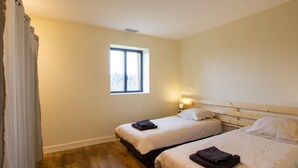 A room with two beds, a window, and a curtain.