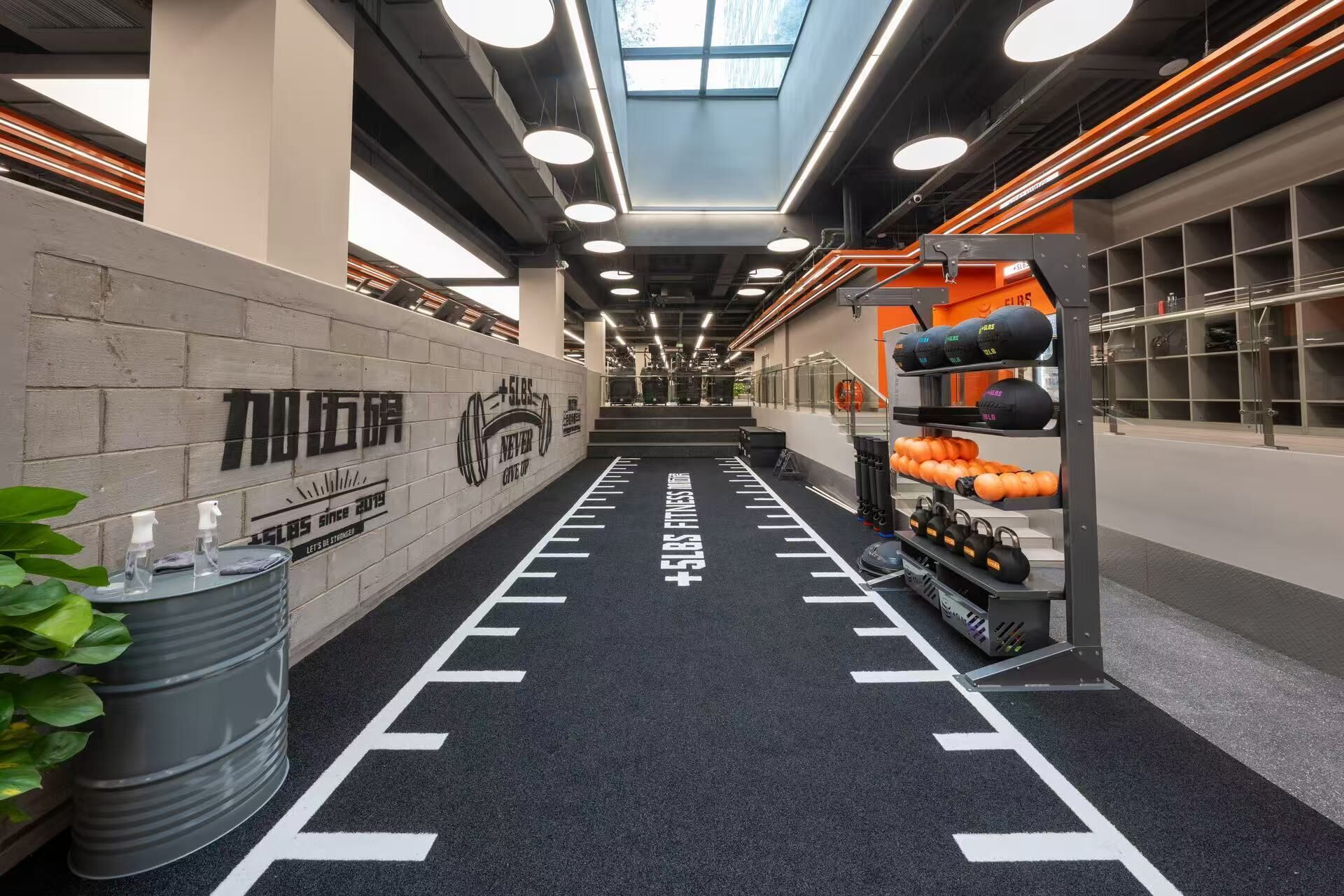 A gym with a black rubber floor, weightlifting equipment, and motivational wall art.
