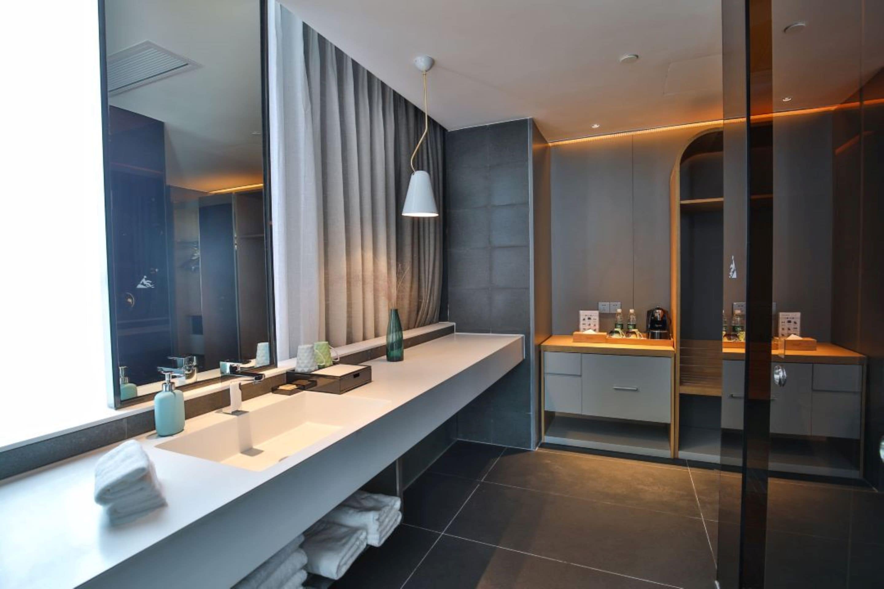 Un baño moderno con un tocador amplio, un espejo grande y una zona de ducha.