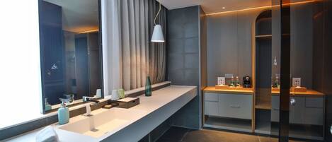 Un baño moderno con un tocador amplio, un espejo grande y una zona de ducha.