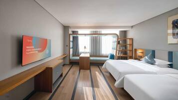Una habitación de hotel con cama, mesitas de noche, escritorio, televisor, estantería y ventana con cortinas.