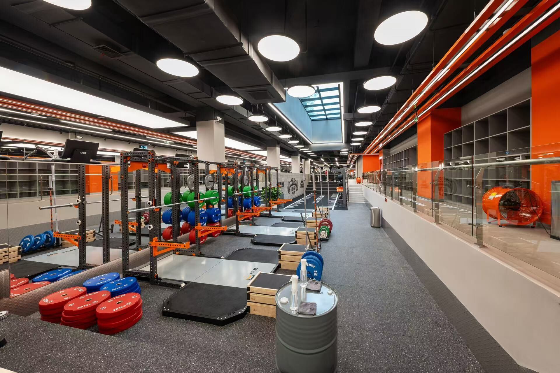 A gym with weightlifting equipment, treadmills, and a large mirror.