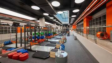 A gym with weightlifting equipment, treadmills, and a large mirror.