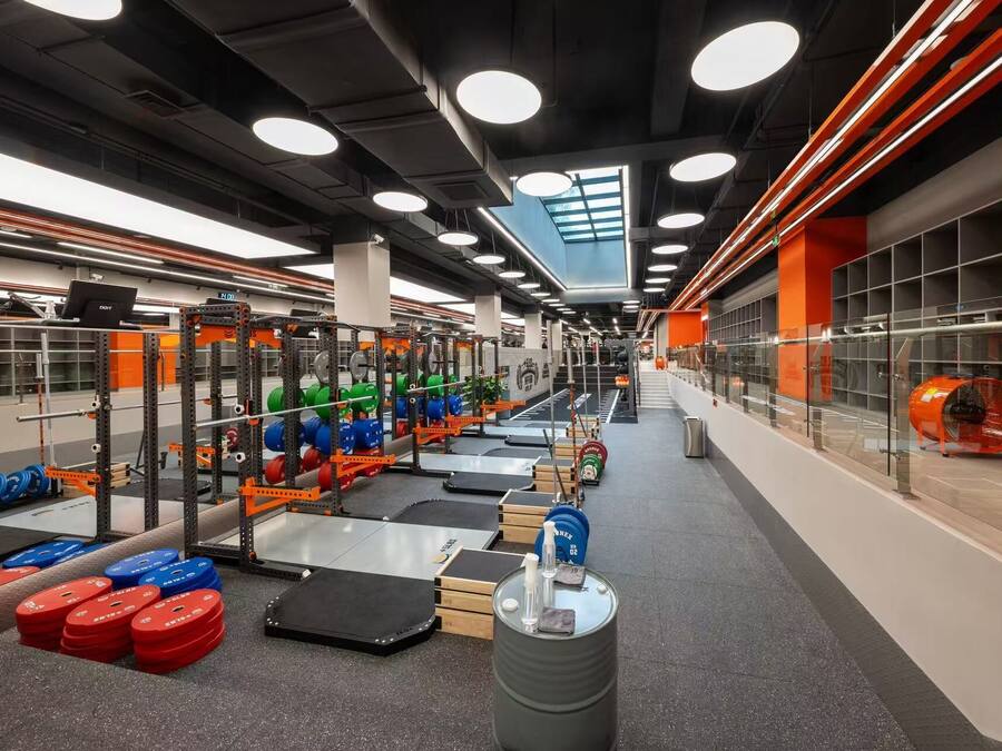 A gym with weightlifting equipment, treadmills, and a large mirror.