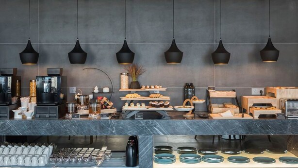 A modern café with marble countertops, black pendant lighting, and a variety of food and drink options.