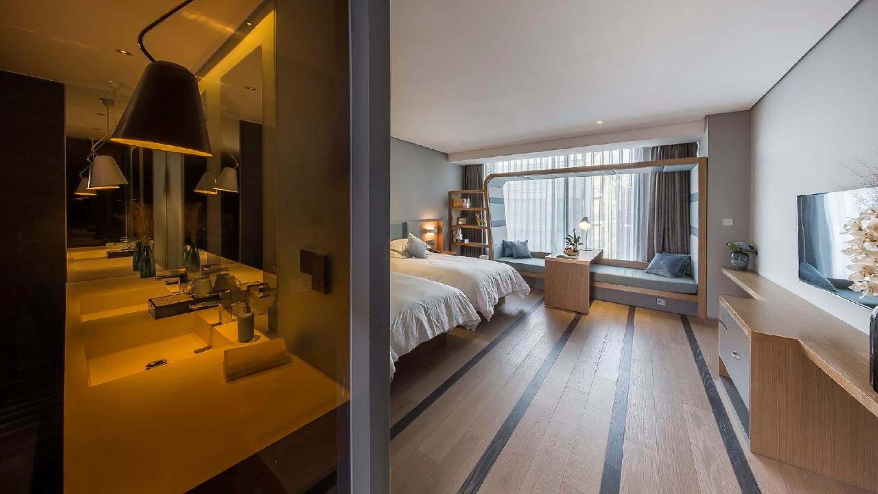 A modern hotel room with a large bed, bedside tables, a desk, and a window with curtains.