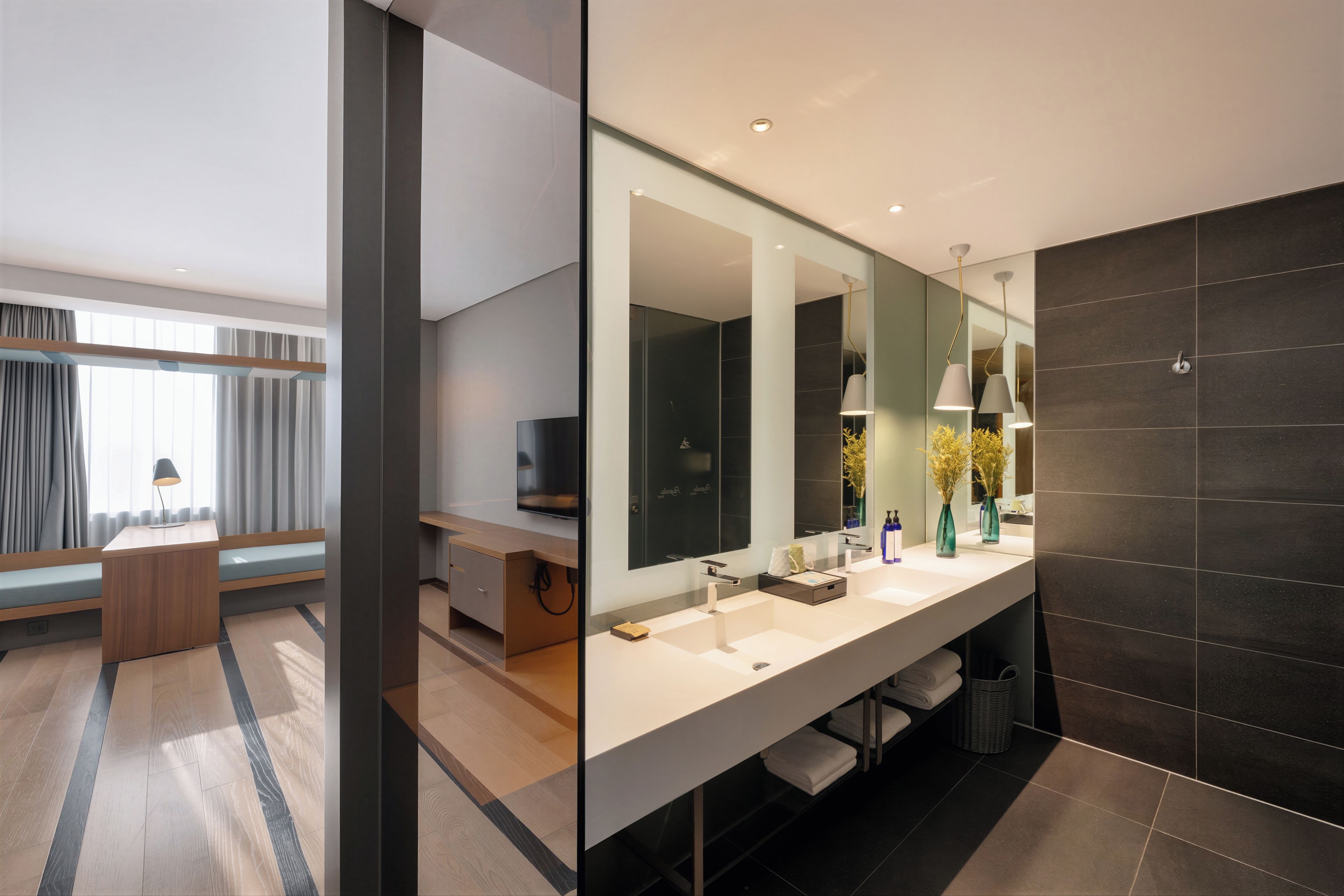 Un baño moderno con un espejo grande, lavamanos dobles y una pared de azulejos oscuros.