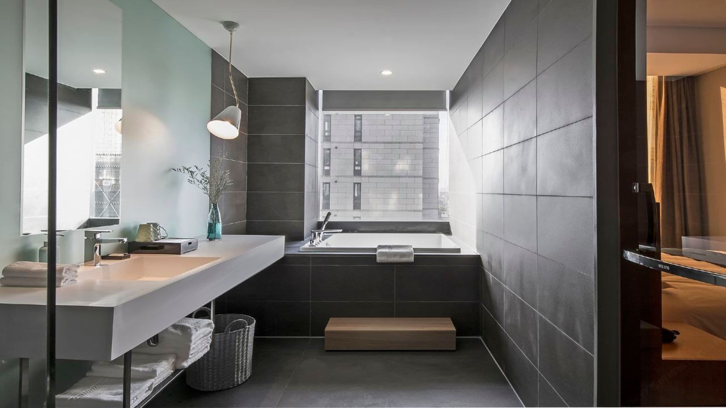 Ein modernes Badezimmer mit großem Spiegel, Waschbecken, Badewanne und einem Fenster für natürliches Licht.