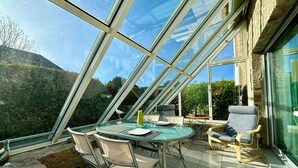 Una veranda con tetto in vetro, un tavolo rotondo e sedie.
