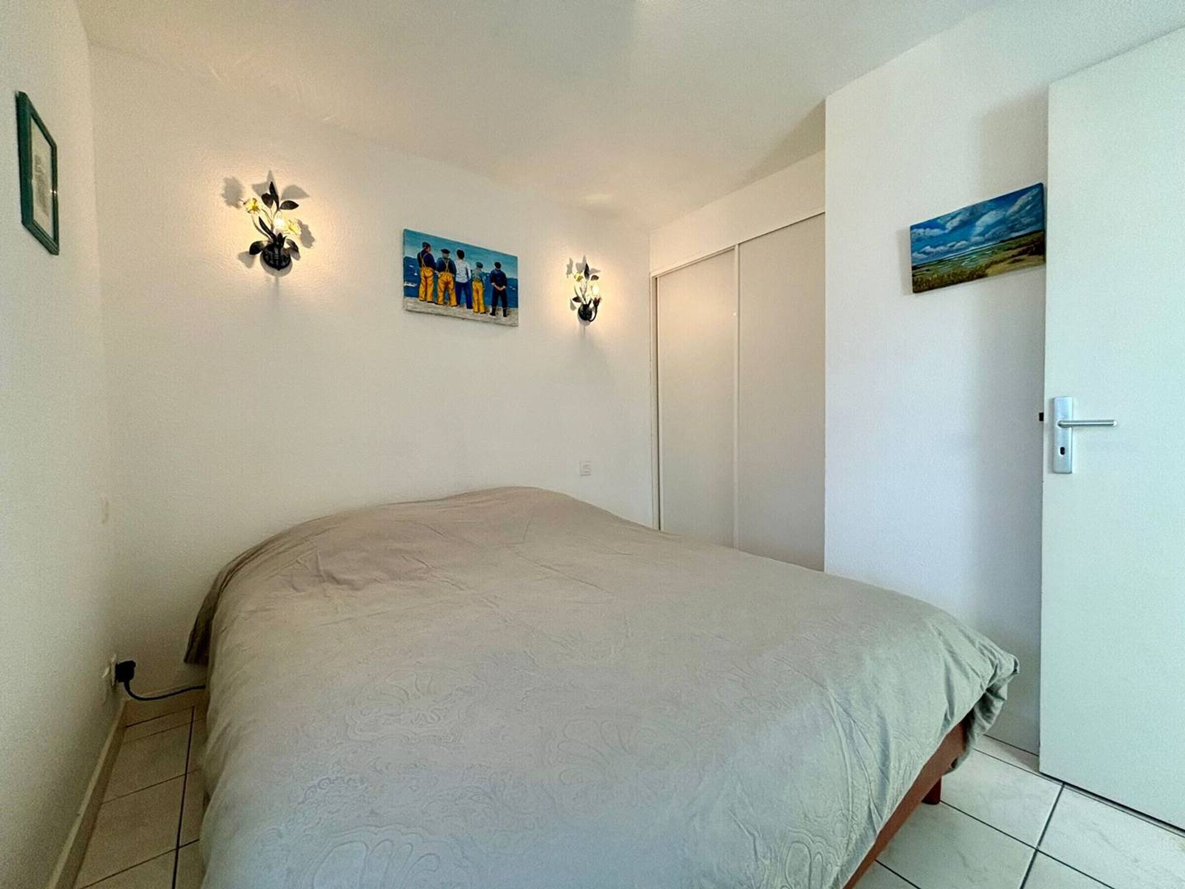 A bedroom with a bed, a wardrobe, and two wall-mounted light fixtures.