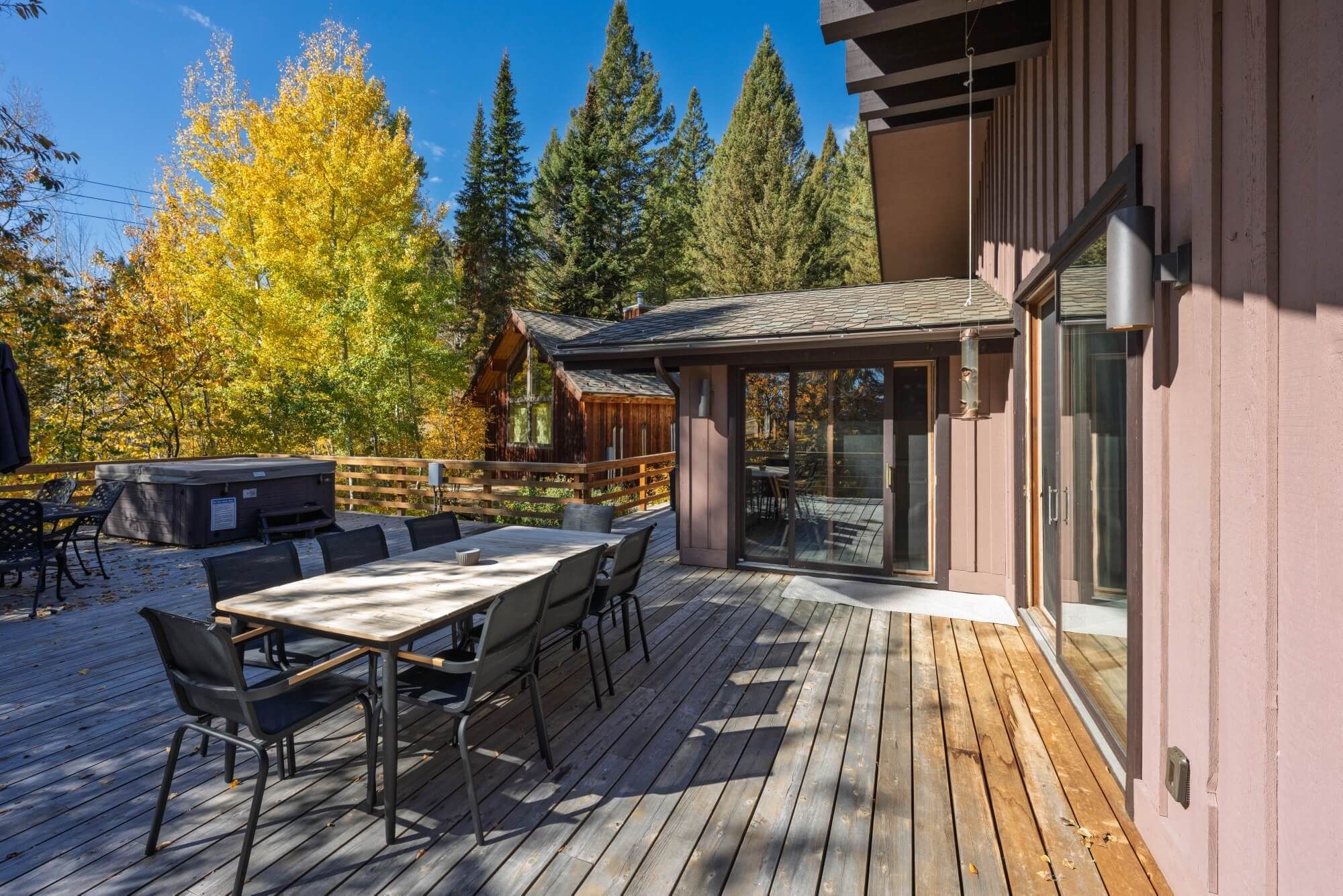 A wooden deck with a table and chairs, a grill, and a glass-enclosed patio area.