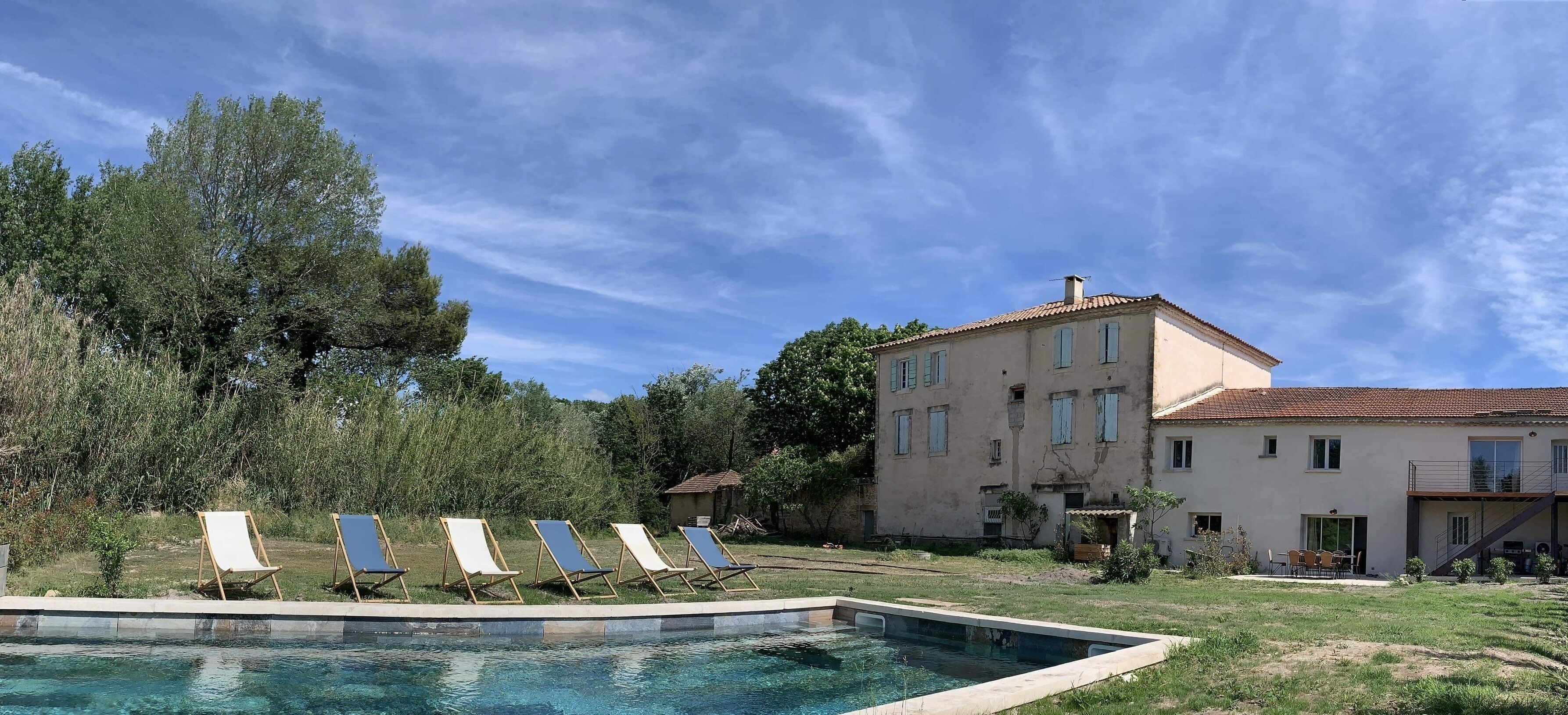 Un espace piscine avec des chaises longues et un grand bâtiment en arrière-plan.