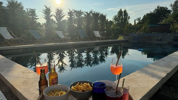 Angolo piscina con tavolo su cui sono disposti bevande, snack e un vassoio.