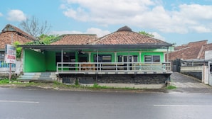 Un edifici verd amb teulada de rajola, un balcó i un cartell de perruqueria.