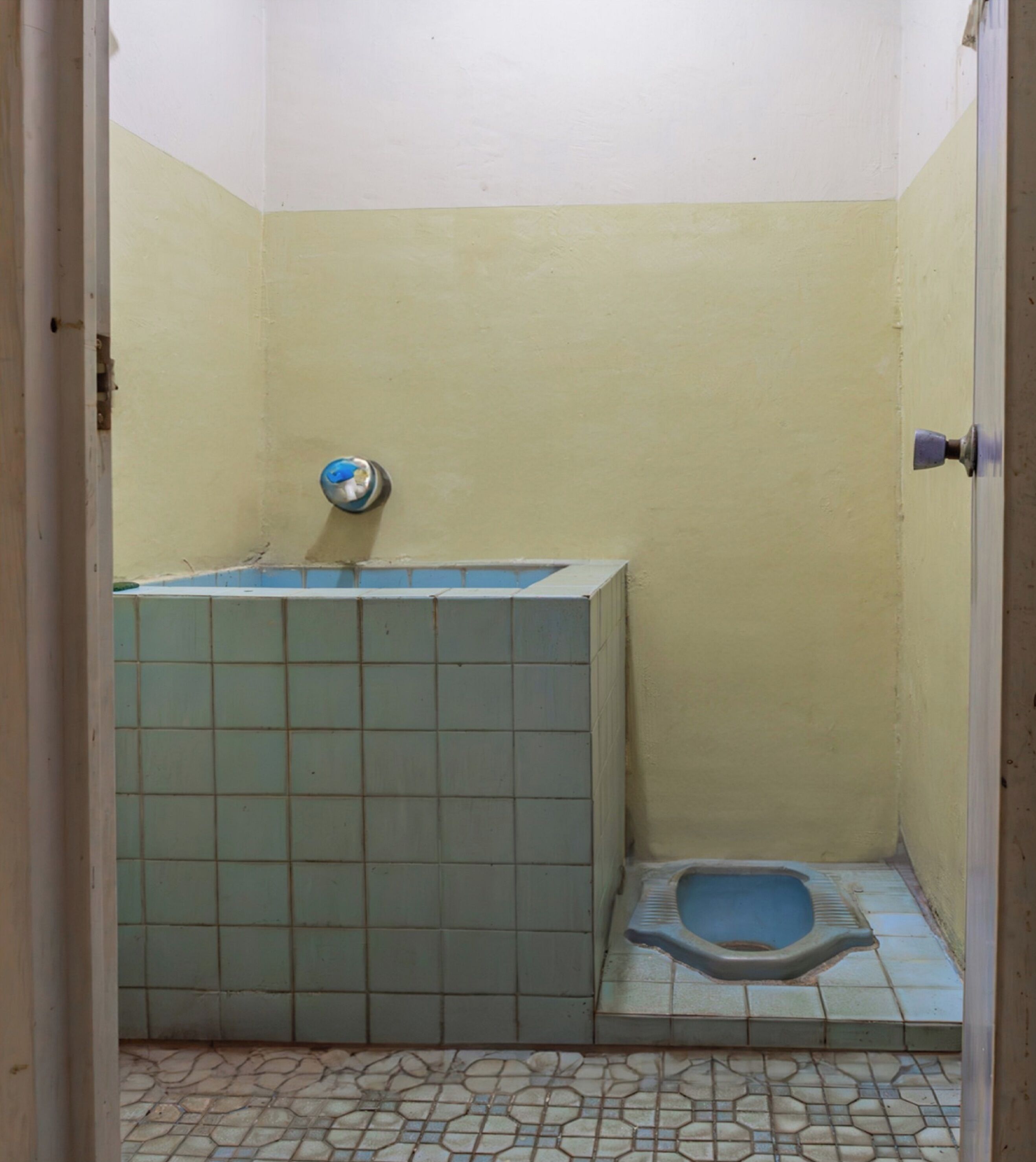 A small, tiled bathroom with a toilet and a sink.