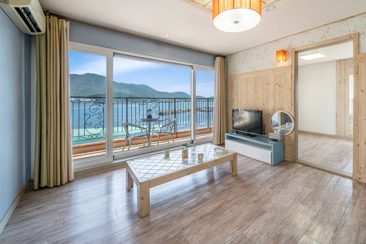 Amplia habitación con un gran ventanal corredero que da a un balcón con vistas al mar y a las montañas.