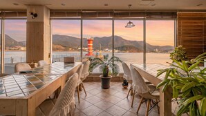 A dining area with a view of a lighthouse and mountains. - Tongyeong Haegando Pension (Tongyeong)