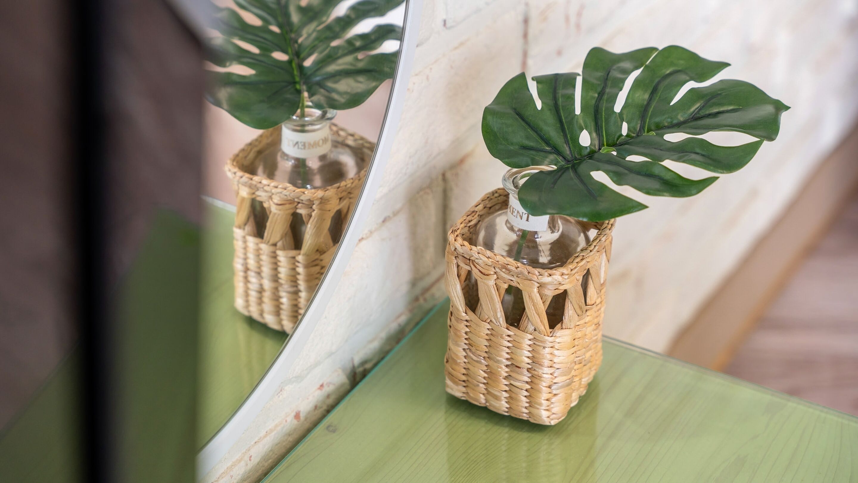 A potted plant in a woven basket on a green surface.