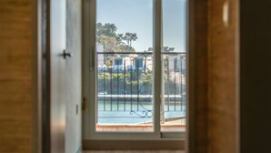 A view through a window with a metal railing, overlooking a body of water, a building with multiple windows, and some greenery. - Tongyeong Haegando Pension (Tongyeong)