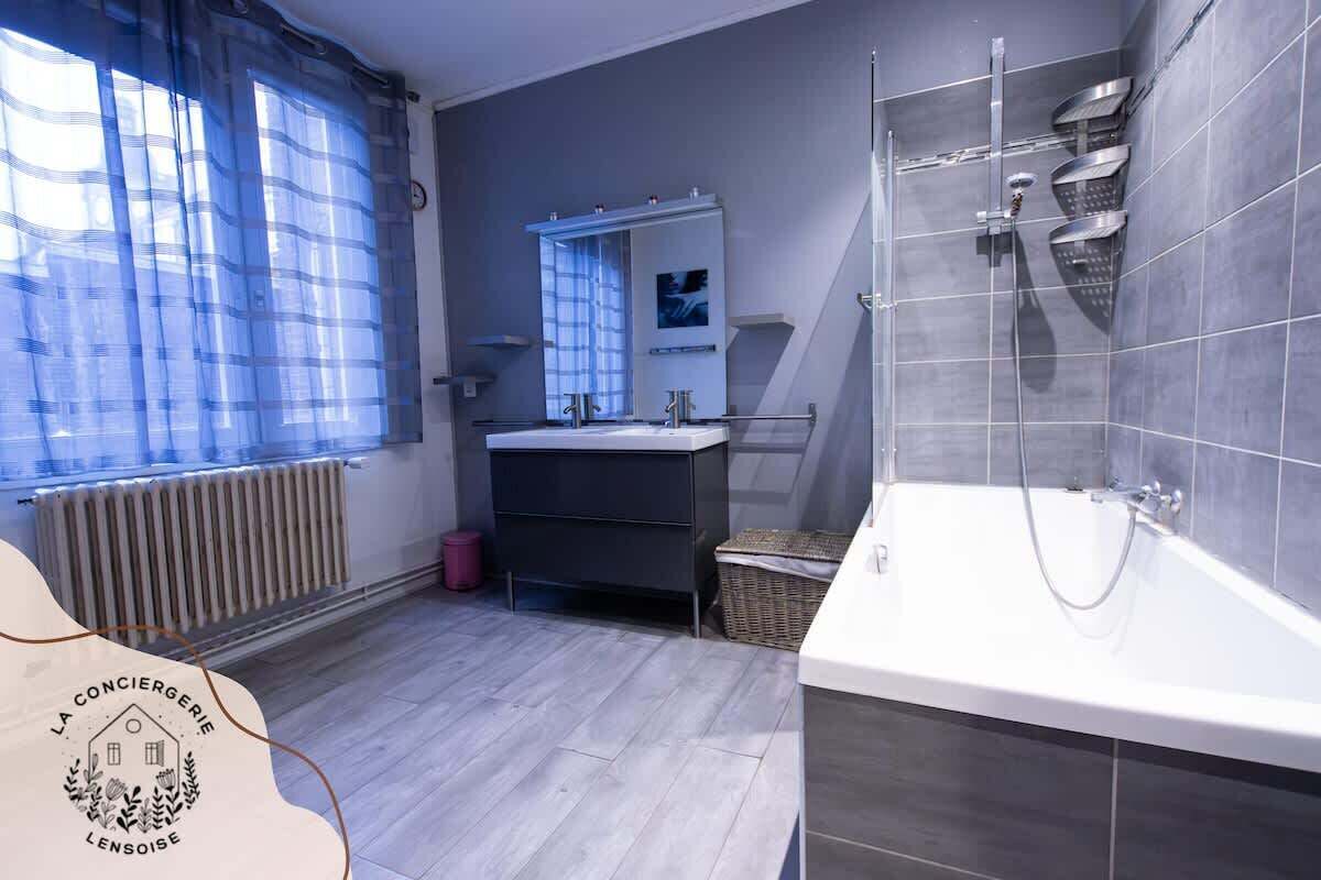 Une salle de bain moderne équipée d’une baignoire, d’une douche et d’un meuble-lavabo avec un miroir.
