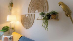 A room with a blue sofa, a hanging plant, a lamp, and wall-mounted shelves with plants. - Sublime 2, Bollaert, 4 pers, centre ville (Lens)