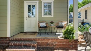 Eine Veranda mit zwei Stühlen, einem kleinen Tisch und einem Blumentopf.