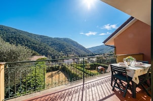 Balcón con mesa lista para comer, con vistas a un paisaje montañoso.