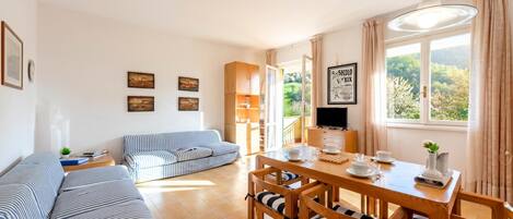 A cozy living area with a sofa, a dining table with chairs, and a TV.