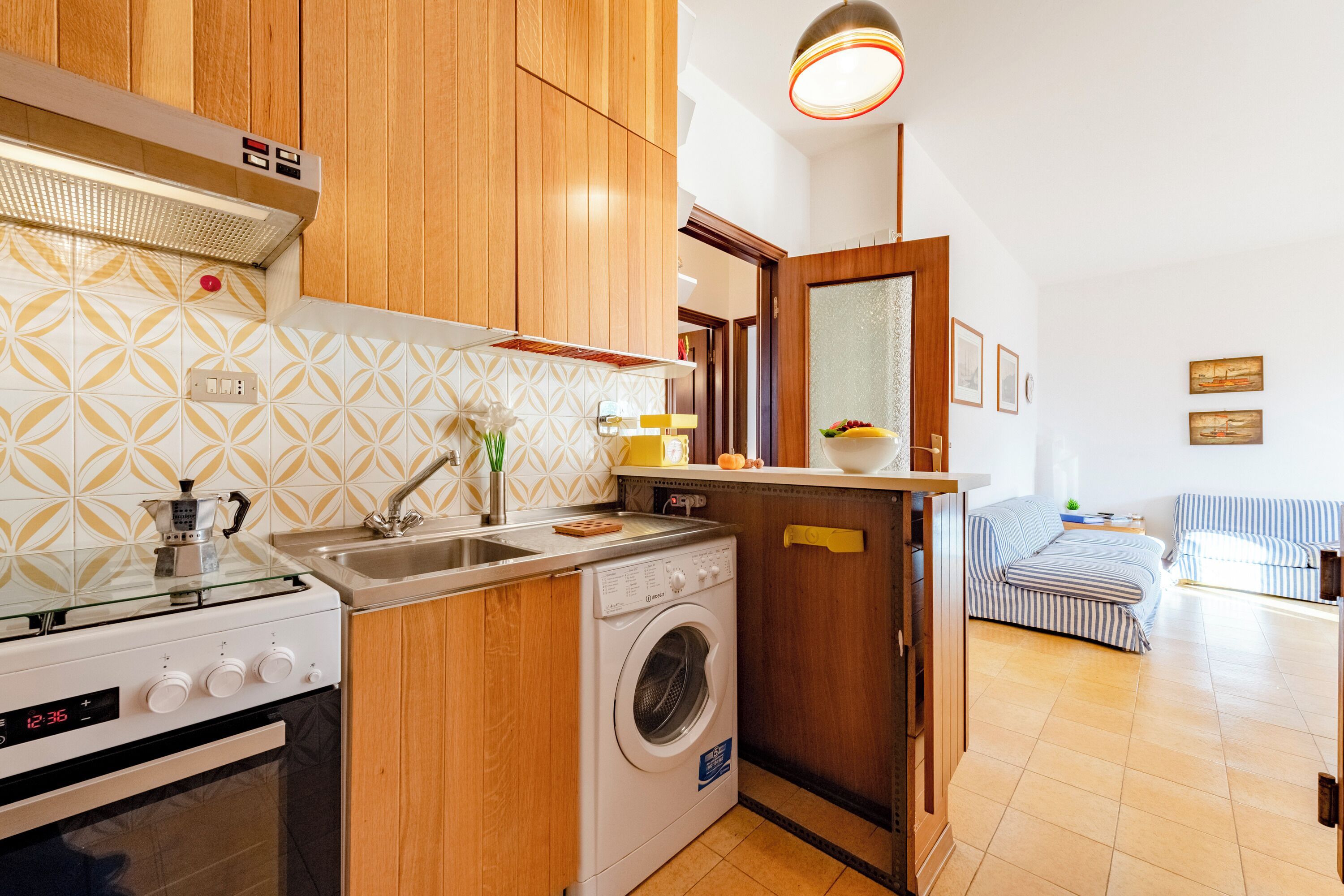 Une cuisine de taille réduite, équipée d’une cuisinière, d’un évier et d’un lave-linge.