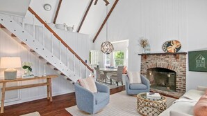 A spacious living room with a fireplace, a staircase, and a dining area.