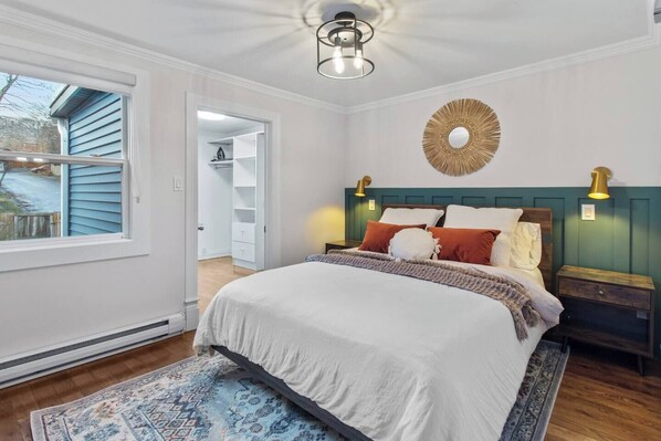 Un dormitorio con cama, vestidor y vistas al exterior.