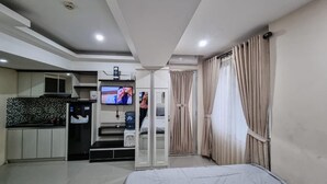 A compact hotel room with a kitchenette, a bed, and a TV.