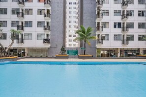 Un immeuble d’appartements moderne doté de balcons, d’une piscine et d’un palmier.