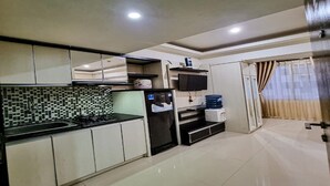 A compact kitchen with a tiled backsplash, a refrigerator, a stove, and a water dispenser.