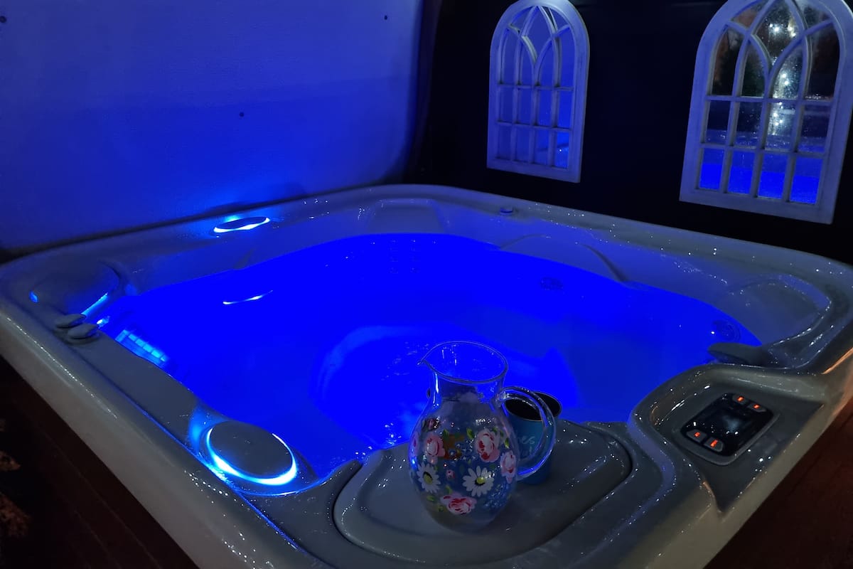 A hot tub with a blue light, a floral vase, and a cup on a tray.