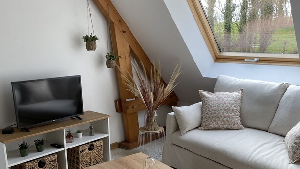 Ein modernes Wohnzimmer mit Fernseher, Couchtisch aus Holz und einer Couch.