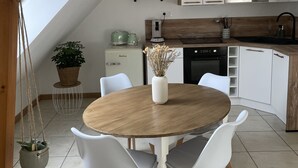 Eine moderne Küche mit weißen Schränken, einem Holztisch und einer hängenden Pflanze.