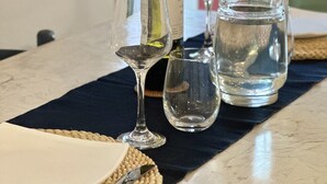 Una mesa dispuesta con una botella de vino, copas, una jarrón y cubiertos.