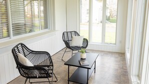 Een zonnedek met twee zwarte wicker fauteuils, een zwarte tafel en een witte vaas met een plant.