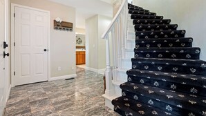 Un escalier recouvert d’une moquette noire, avec des balustrades blanches, menant à un deuxième étage.