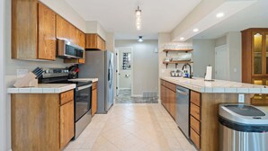 Une cuisine moderne avec des meubles en bois, des appareils électroménagers en acier inoxydable et un sol carrelé.