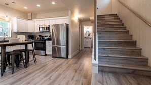 Una cocina moderna con armarios blancos, electrodomésticos de acero inoxidable y una escalera de madera.