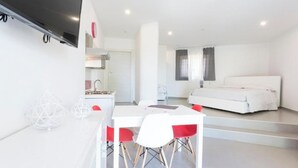 A modern, well-lit room with a dining area, a bed, and a kitchen.