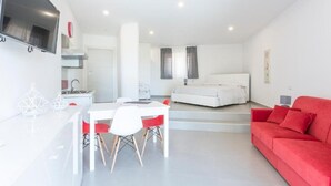 A modern living space with a dining area, a sofa, and a TV mounted on the wall.