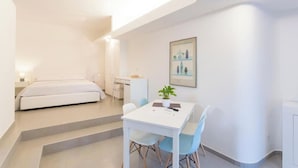 Una habitación de hotel moderna con una cama, un escritorio y una zona de comedor con sillas.